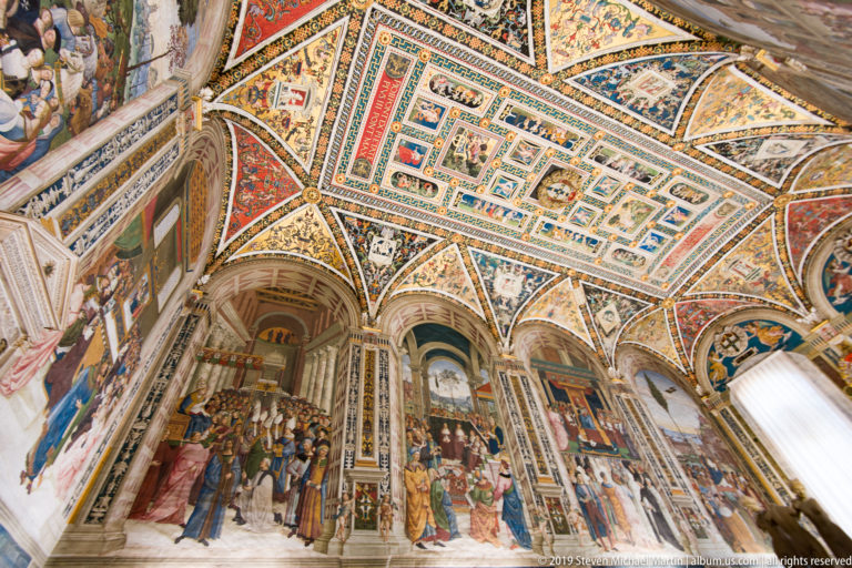 An elevated view shows a central pavement panel beneath painted walls and the cathedral’s decorated vault.