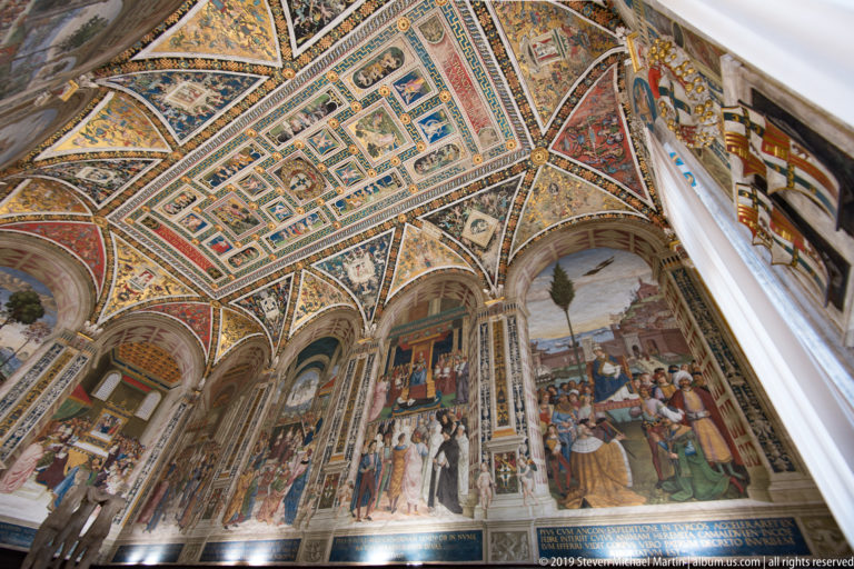 Painted scenes cover the cathedral vault and side bays above a distant section of pavement.