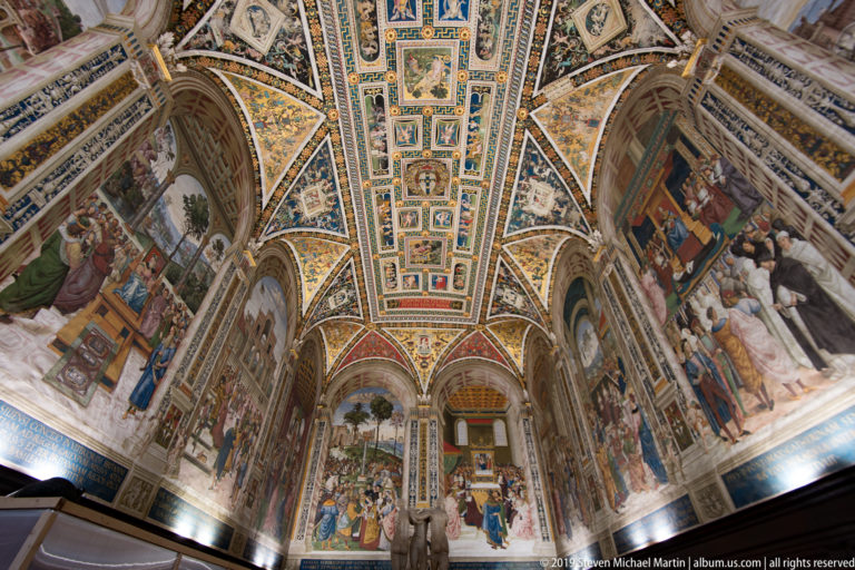 A symmetrical view from the inlaid pavement up the nave to the painted and gilded ceiling.