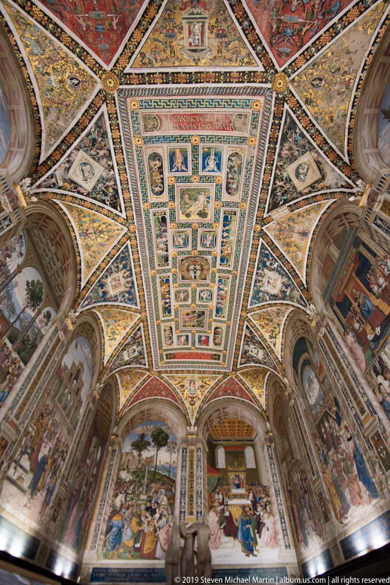 A long central ceiling panel is surrounded by gold-trimmed scenes and painted triangular vault sections.