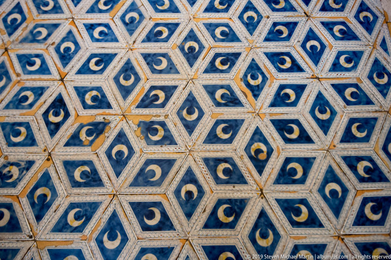 Pale crescent shapes repeat across blue geometric panels on the cathedral ceiling.