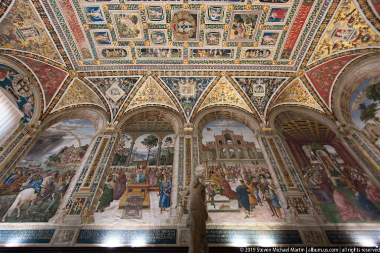 Framed paintings run along the vault above larger narrative scenes in the cathedral’s side bays.