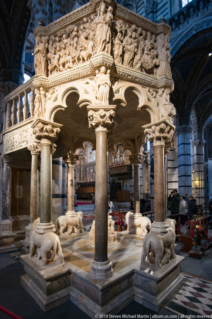 A marble pulpit with carved lions at its base stands inside the striped nave.