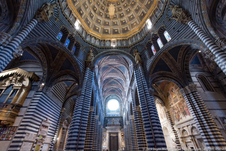 The cathedral’s striped piers and pointed arches lead toward a bright apse and altar.