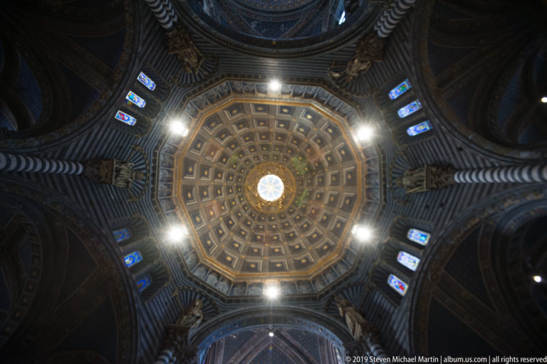 A small blue ceiling medallion sits within concentric gold-trimmed panels above the nave.