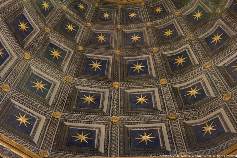 Gold stars sit within dark blue geometric ceiling panels bordered by carved mouldings.