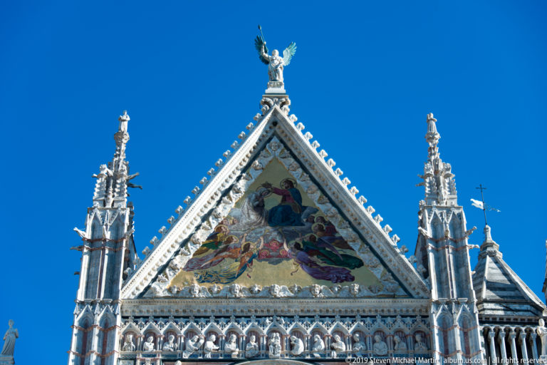 A central robed figure and attendants appear in a triangular mosaic above the cathedral façade.