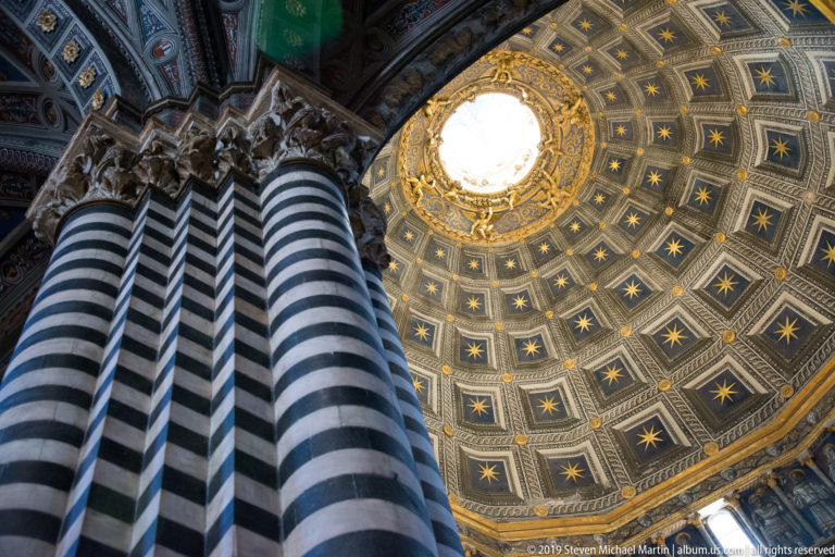 Striped piers support a blue star-patterned vault with a gilded sunburst around its center.