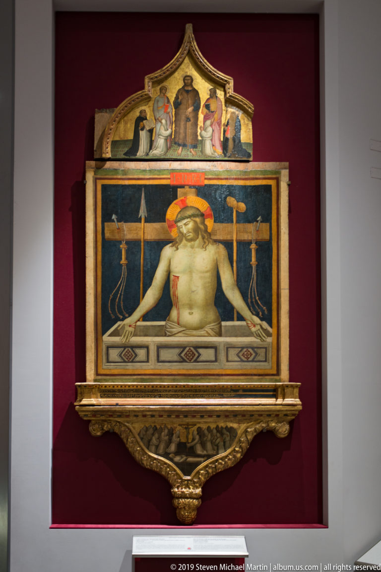 Half-length wounded Christ rises from a tomb beneath a halo, surrounded by instruments of the Passion in a gilded frame.