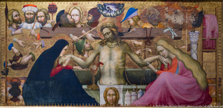 Painted scene of the dead Christ supported between grieving women, with Passion imagery filling the background.
