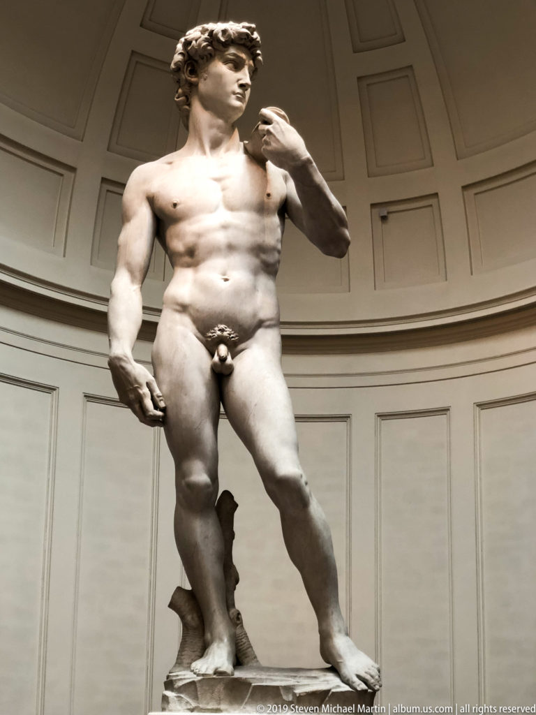 Closer frontal view of Michelangelo’s David, emphasizing the torso, hands, turned head, and contrapposto stance.