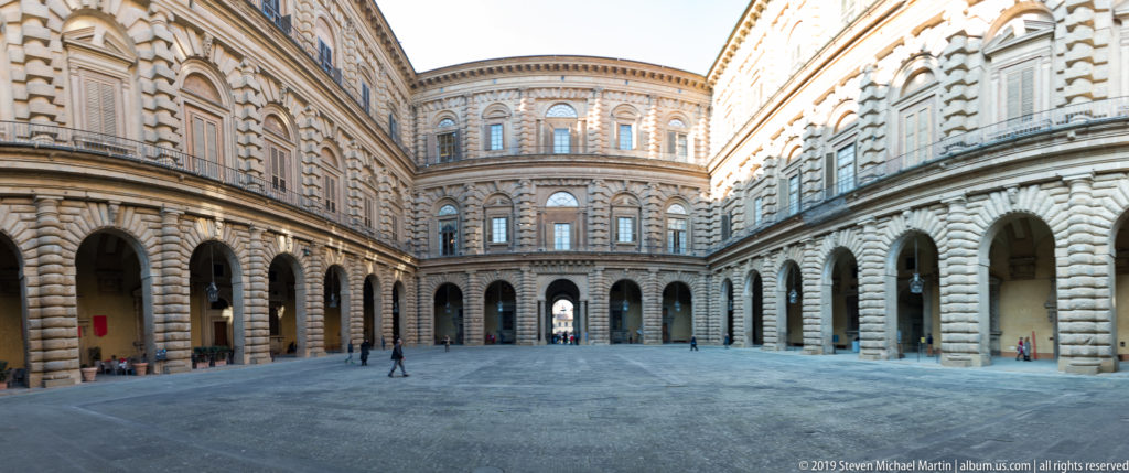 Broad Pitti Palace courtyard enclosed by rusticated arcades and multi-story stone façades.