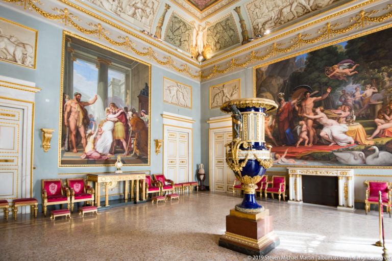 Large framed or ceiling painting with multiple figures in a richly decorated Pitti Palace interior.