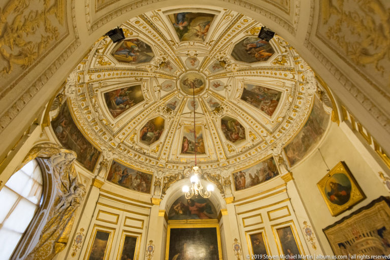Shallow dome with wedge-shaped fresco panels radiating from the center between white-and-gold ribs.