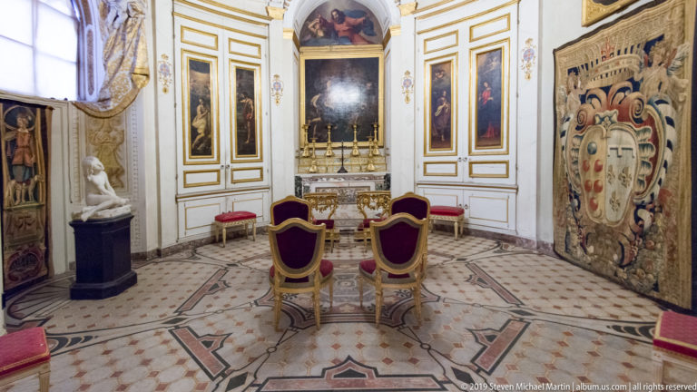 Large framed or ceiling painting with multiple figures in a richly decorated Pitti Palace interior.