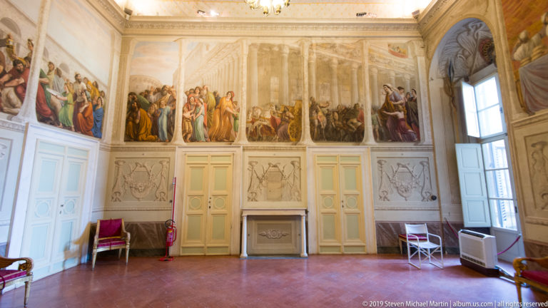 Long decorated palace gallery with sculpture displays, chandeliers, and architectural ornament.