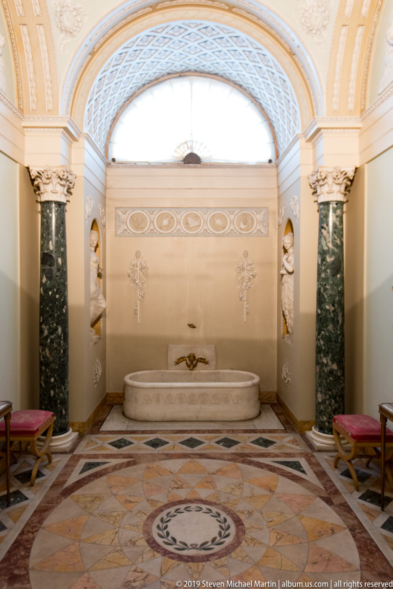 Stone bath centered between dark green marble columns with Corinthian capitals in Napoleon’s Bathroom at Pitti Palace.