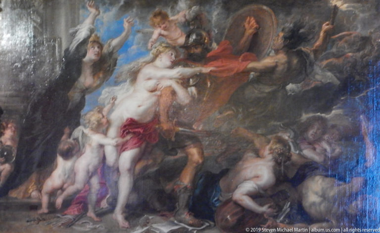 Large dark mythological painting crowded with nude figures, drapery, animals, and vigorous diagonal movement.