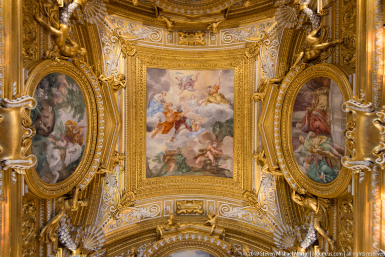Gilded ceiling bay with a rectangular central fresco, oval side paintings, sculpted figures, scrolls, and shells.