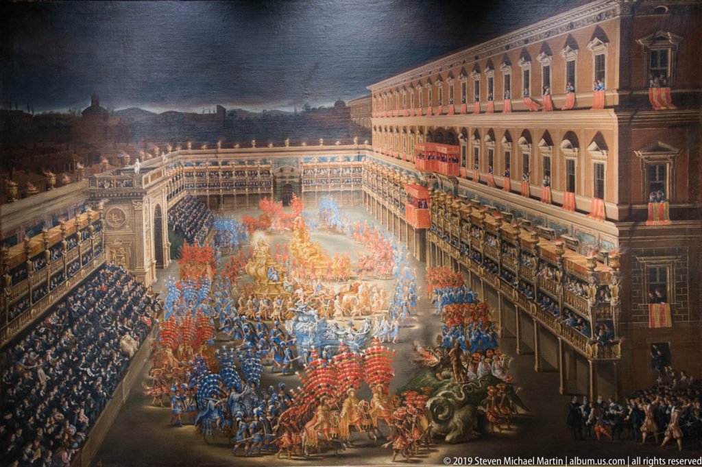 Large dark painting of a city square filled with red and blue costumed crowds, balconies and a richly decorated procession.