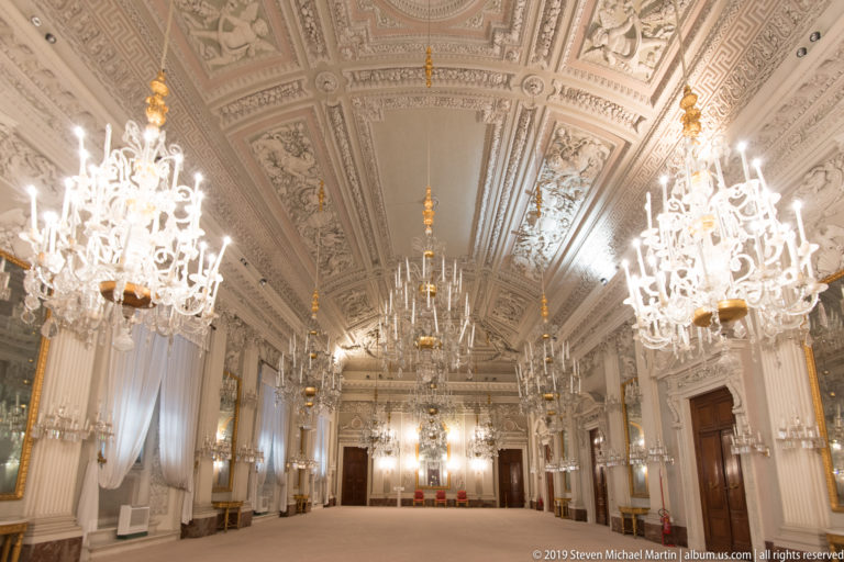 Central axial view through Pitti Palace’s White Hall, with symmetrical crystal chandeliers and richly modeled pale Neoclassical stuccowork.