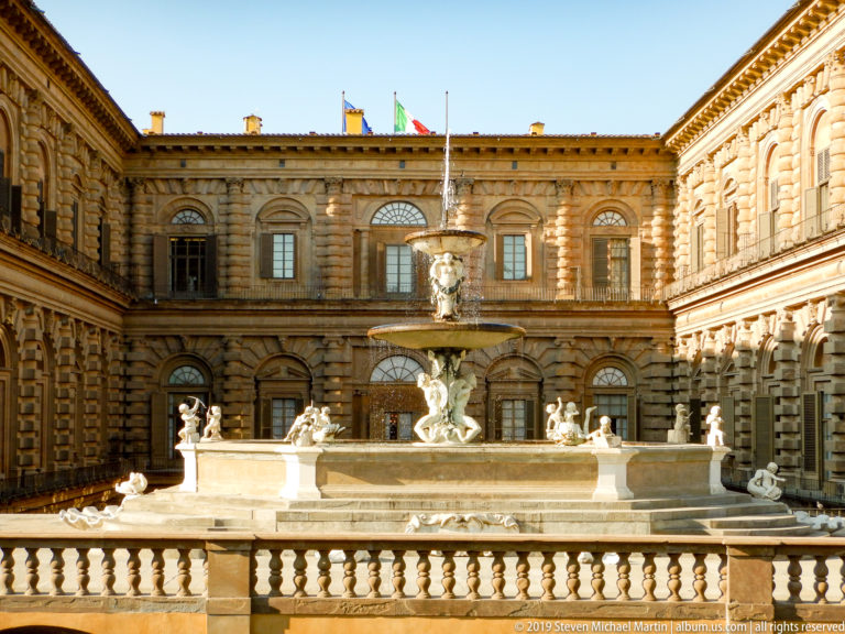 Artichoke Fountain centered in Pitti Palace’s rusticated courtyard, with sunlit stone façades surrounding the sculptural basin.