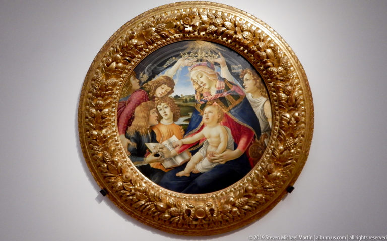 Botticelli’s framed Madonna of the Magnificat, with angels crowning Mary as she writes beside the Christ Child and pomegranate.