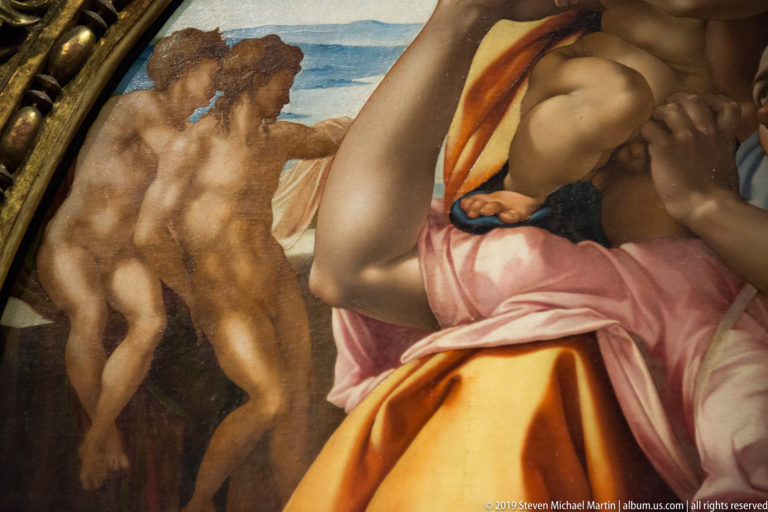 Detail of Michelangelo’s Doni Tondo with Mary’s vivid drapery in front of nude youths seated beyond a low wall.