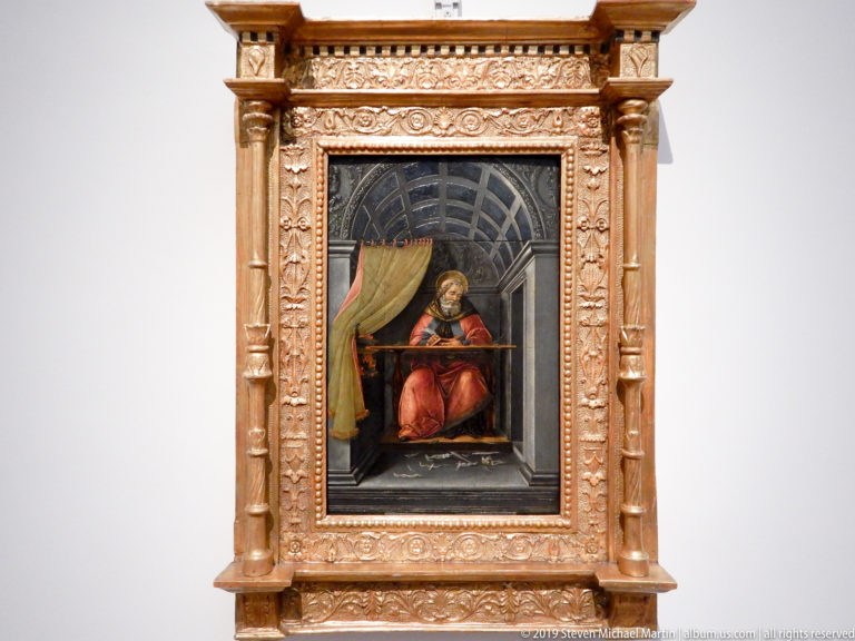 Bearded Saint Jerome in a red robe reads at a desk inside a deep coffered architectural study.