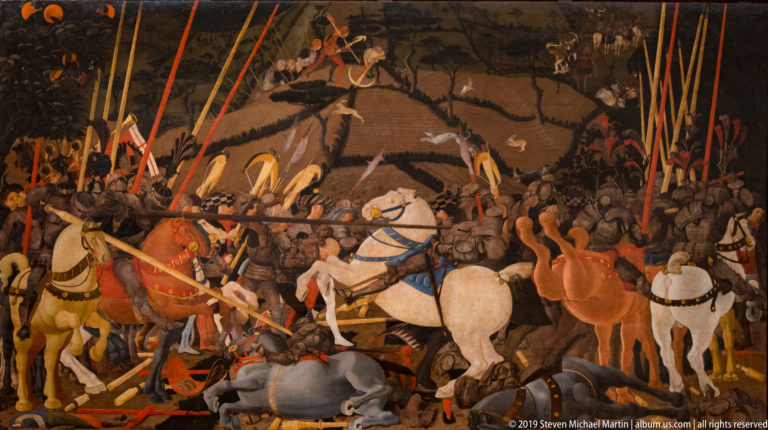 Crowded cavalry battle with armored riders, pale horses, fallen soldiers, and a forest of red and orange lances.