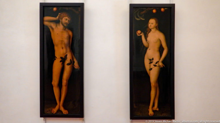 Two narrow paintings of nude Adam and Eve standing separately against dark backgrounds with leaves and fruit.