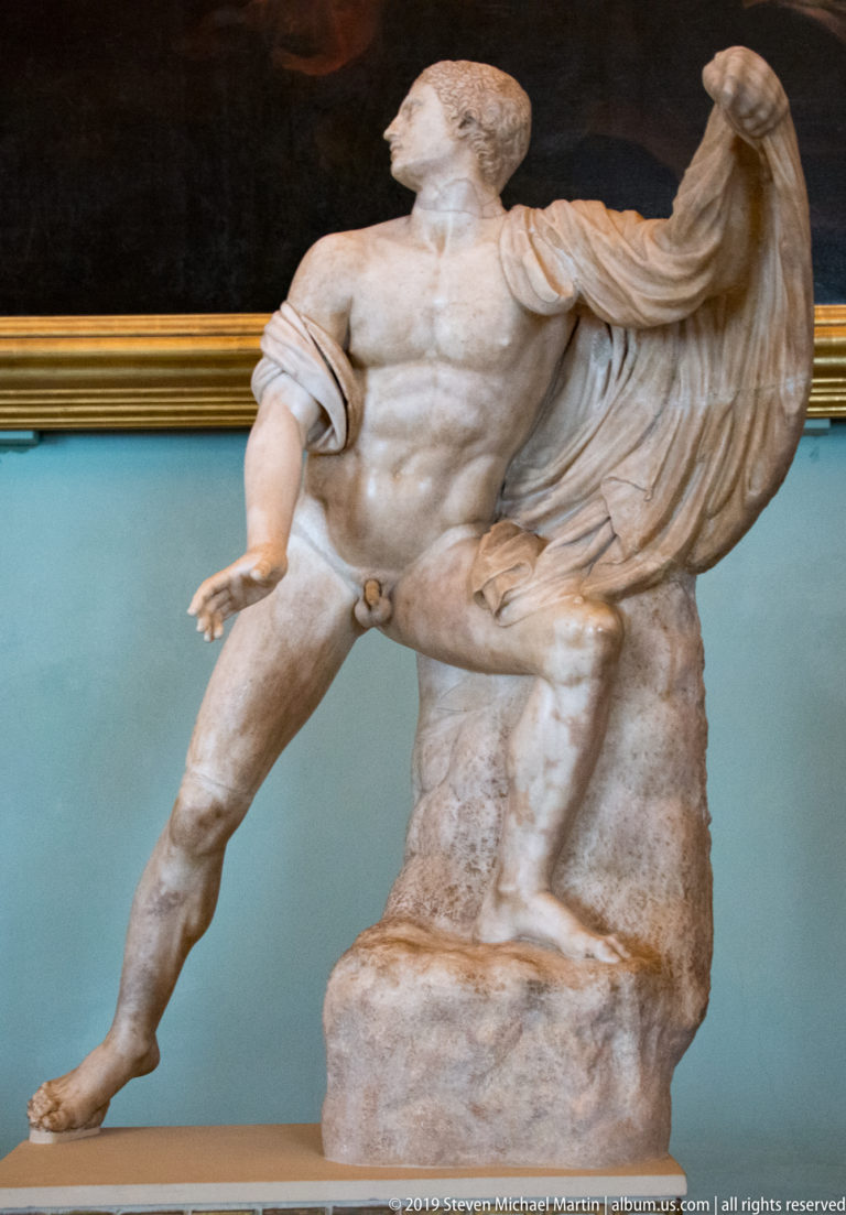 Marble group with a muscular nude male leaning beside a heavily draped, partially preserved companion.