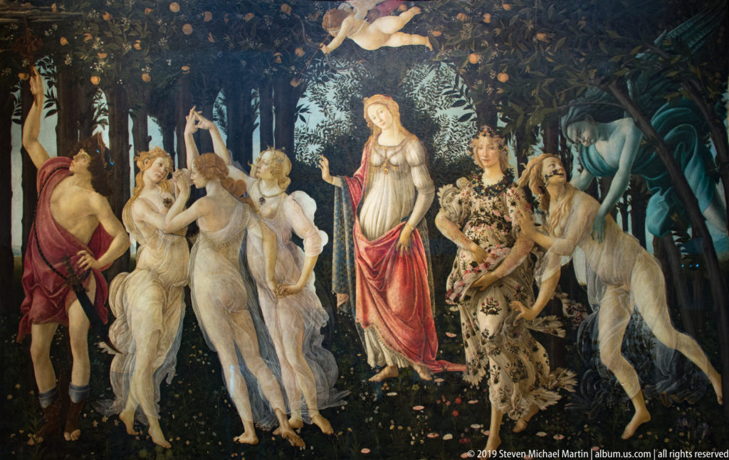 Botticelli’s Primavera with Venus and Cupid centered between the Three Graces and Mercury at left and spring figures at right.