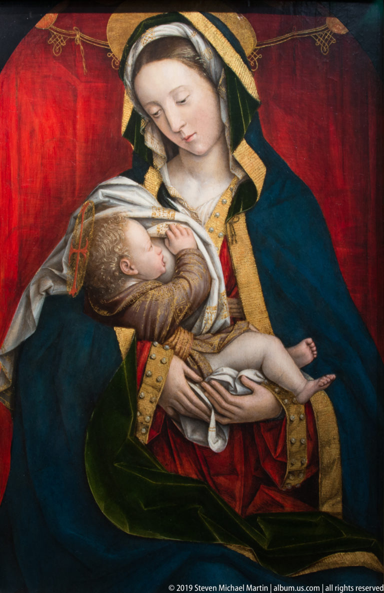 Virgin in blue and green cradling the infant Christ across her lap against a red background.