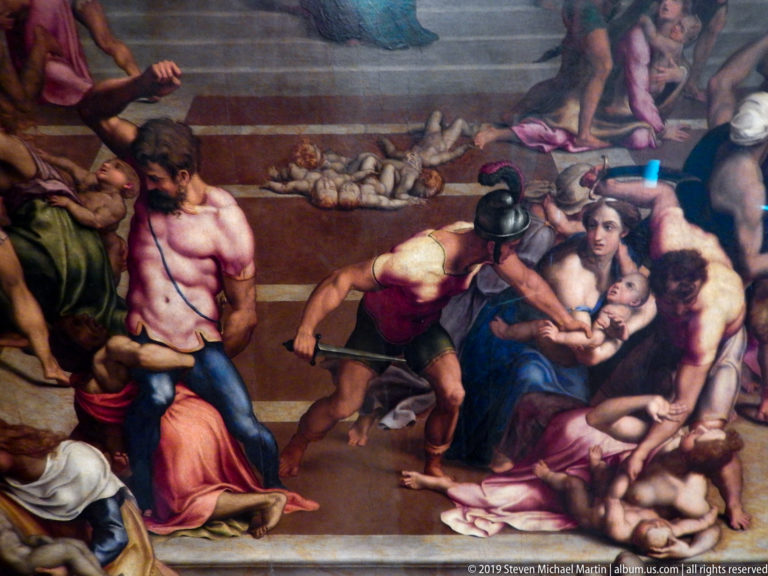 Soldiers attack amid women and infants in a crowded architectural setting with bodies on the ground.
