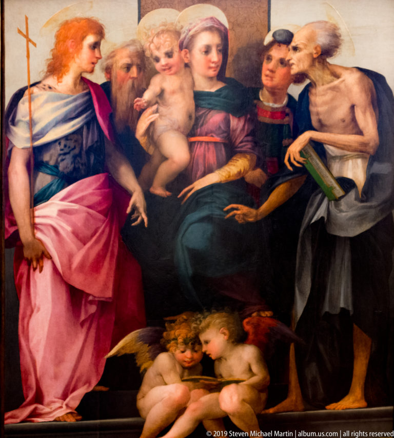 Virgin holding the infant Christ among several saints, with two winged putti seated below.