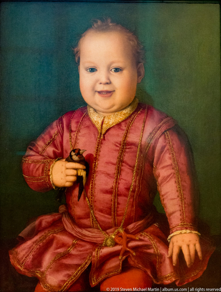 Young child in rose-colored, gold-trimmed court dress against a plain green background.