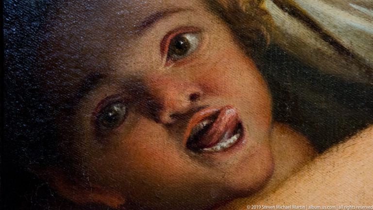 Extreme close-up of a painted woman’s face with wide eyes, flushed cheeks, and parted lips.