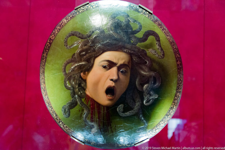 Caravaggio’s Medusa on a convex shield, with writhing snake hair, terrified expression, and blood streaming from the severed neck.