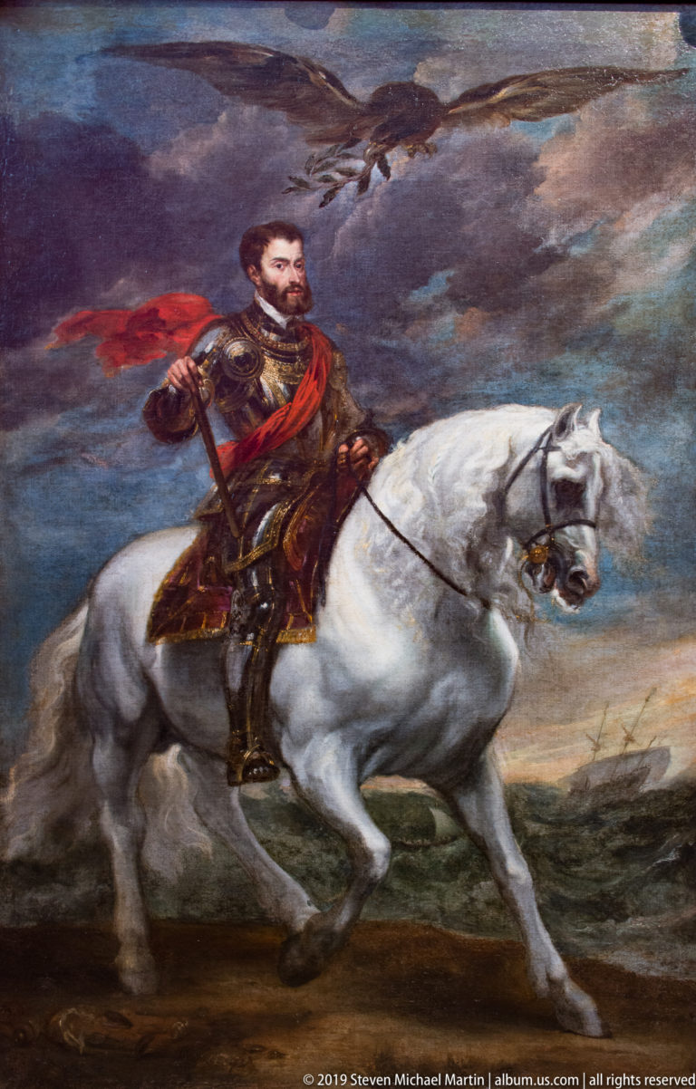 Armored man with red sash riding a white horse across a landscape beneath a dramatic cloudy sky.