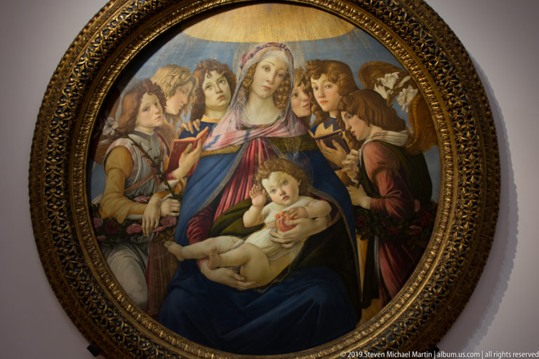 Botticelli’s Madonna of the Pomegranate, with Mary and Christ holding a pomegranate amid six angels in a circular composition.