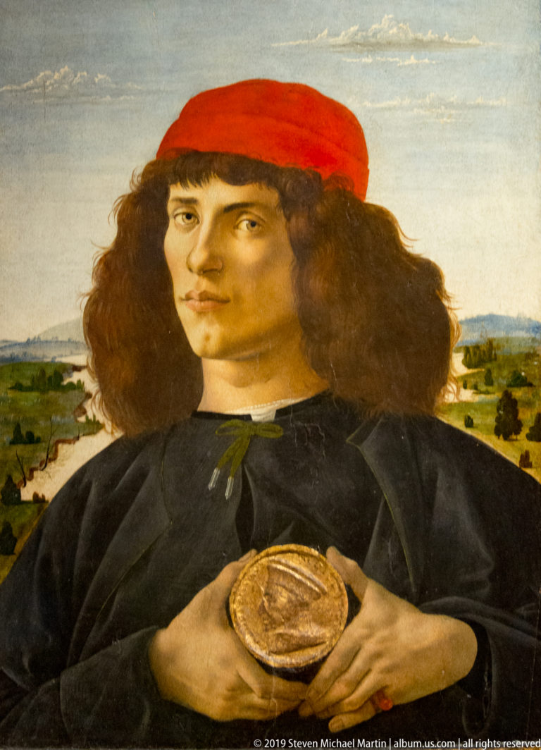 Botticelli’s young man faces forward holding a gilded relief medal of Cosimo de’ Medici against his dark clothing.