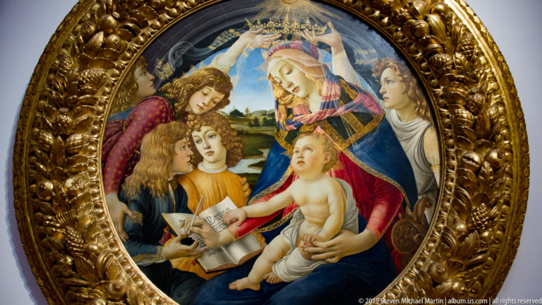Crowned Virgin writes in an open book while holding the Christ Child, surrounded by youthful angels in a gilded tondo.