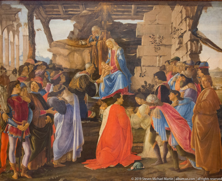 Botticelli’s Adoration of the Magi with the Virgin and Child receiving kneeling kings and a richly dressed Florentine retinue among ruins.