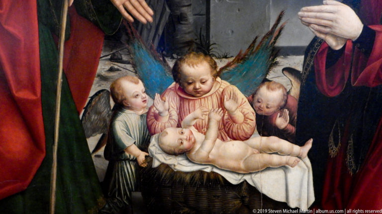 Infant Christ lies in a wicker cradle surrounded by four small angels, with adult figures cropped at the edges.