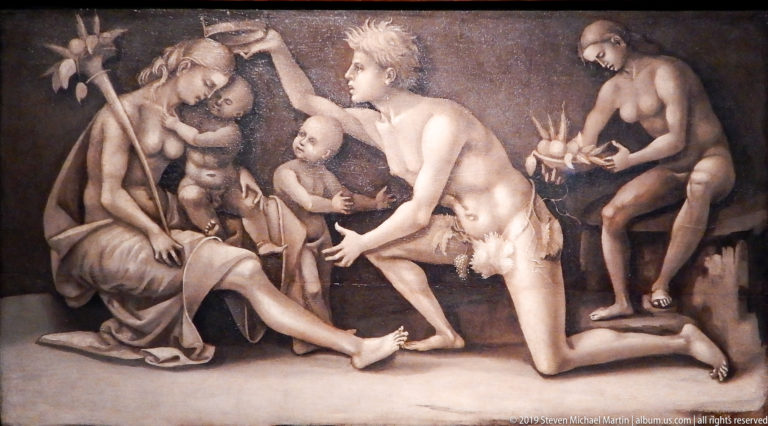 Monochrome group of nude and draped figures clustered around a seated woman, with a kneeling youth at center.