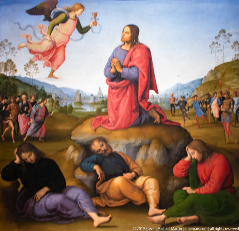 Christ kneels on a rock beneath an angel with a chalice while three disciples sleep and armed men approach.