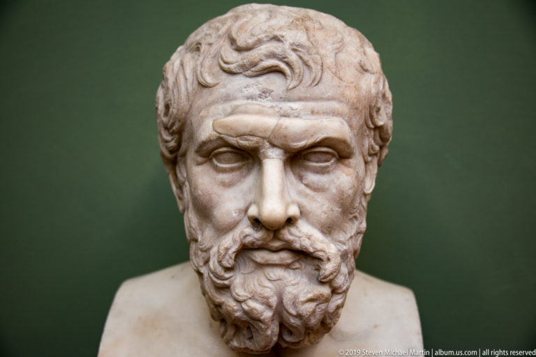 Marble bust of a mature man with swept hair, furrowed brow, mustache, and full curling beard.