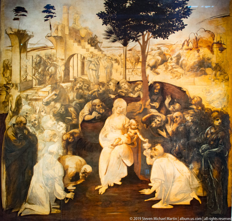 Wide view of Leonardo’s unfinished Adoration of the Magi with the Virgin and Child, kneeling figures, horses, and emerging architecture.