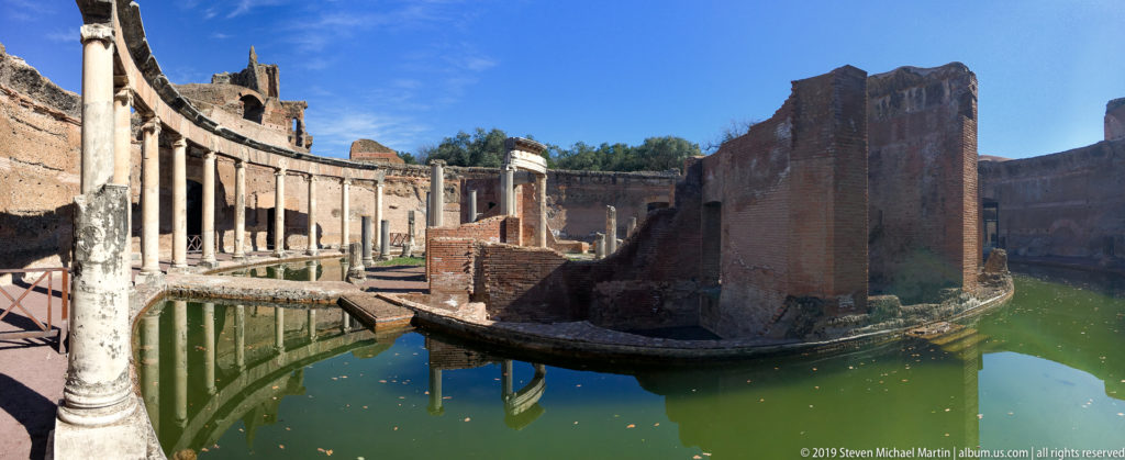 Circular brick island and curved colonnade reflected in the green water of the Maritime Theatre at Hadrian’s Villa.